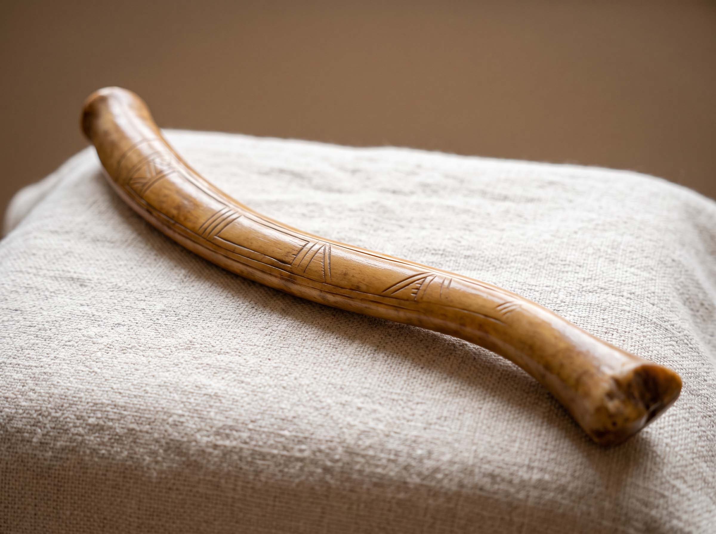 A carved walrus bone tool handle displayed on a neutral cloth surface