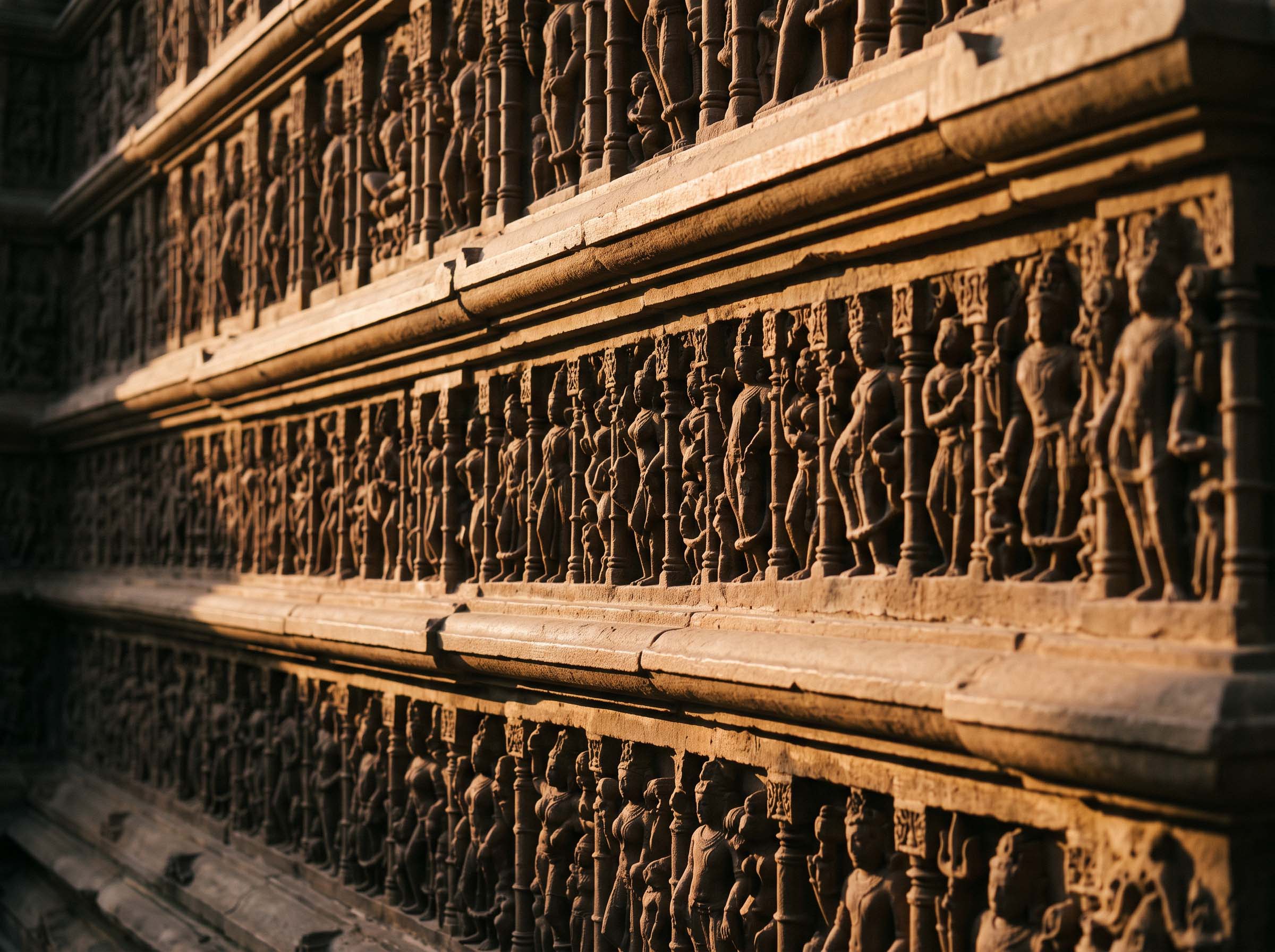 Stacked horizontal bands of high-relief sandstone carving on a temple exterior wall, seen in raking afternoon light