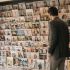 A person standing before a wall of international magazine covers, representing how global media carries body ideals across cultures