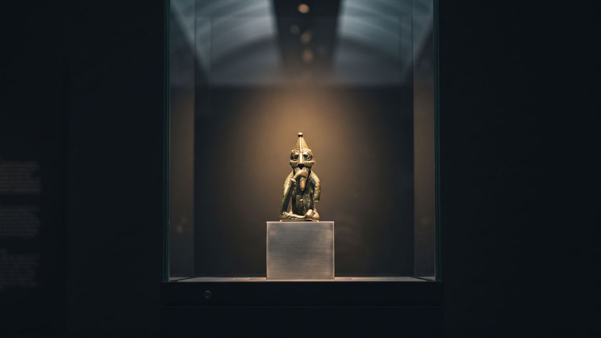 A small Viking Age bronze figurine lit in a museum vitrine, illustrating Norse mythology and the body