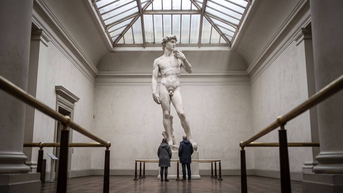 Museum cast court with a towering Renaissance nude sculpture under a skylight, illustrating how art recorded body ideals rather than measured averages