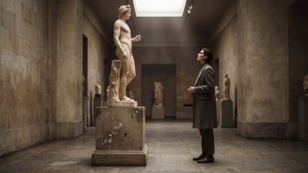 Visitor contemplating a classical marble nude sculpture in a museum, illustrating Renaissance body ideals and the human form in art history