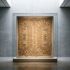 A museum vitrine holding a woven ritual textile used to screen a doorway, lit from above in a quiet gallery